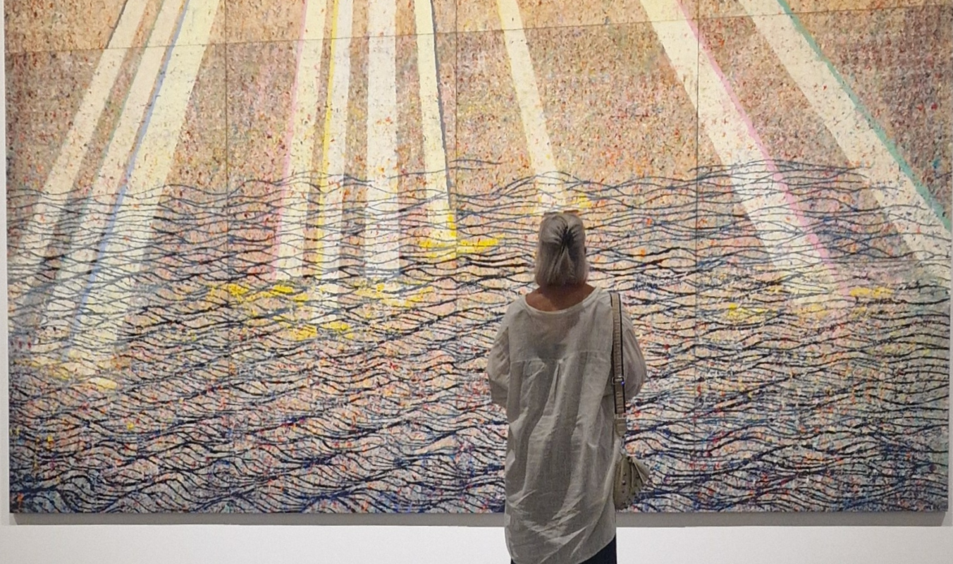 Marion steht mit dem Ruecken zum Betrachter vor einem Gemaelde und bestaunt die Einzelheiten. Dabei wird sie von einem Sonnenstrahl im Bild  beluchtet.